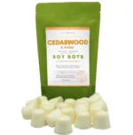 Cedarwood and Amber wax melt dots displayed in front of a rice paper stand-up pouch from Lux Candles & Melts.